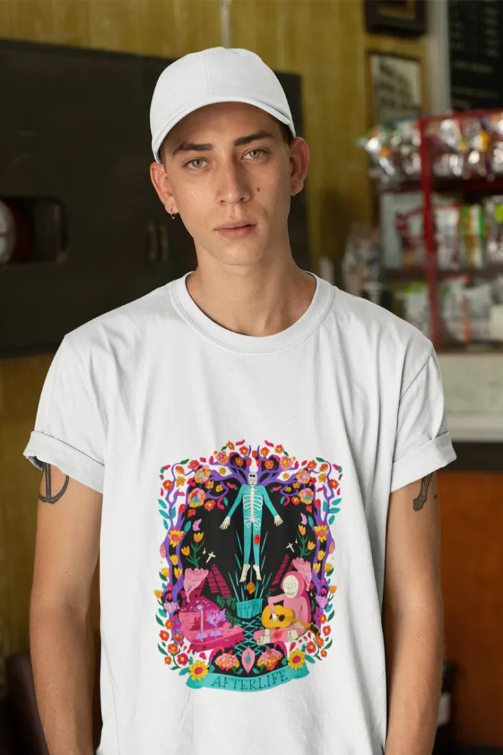 A man wearing a white cap and a printed white t-shirt. The t-shirt design is a psychedelic design with a skeleton man who is floating in mid air and a skeleton playing guitar while sitting. There's a text saying Afterlife at the bootom of the design.