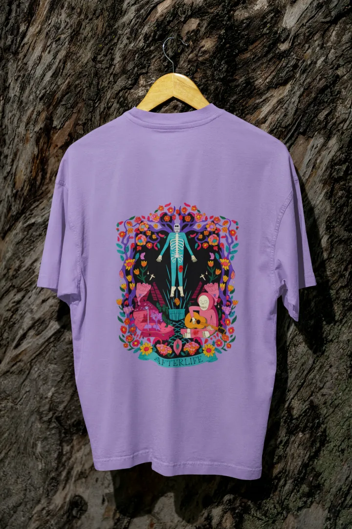 Lavender back printed oversized tee shirt for men hanging on a wooden hanger against a textured background, featuring a colorful psychedelic illustration of two figures—one standing and the other sitting on a bench surrounded by flowers and leaves in vibrant, intricate detail.