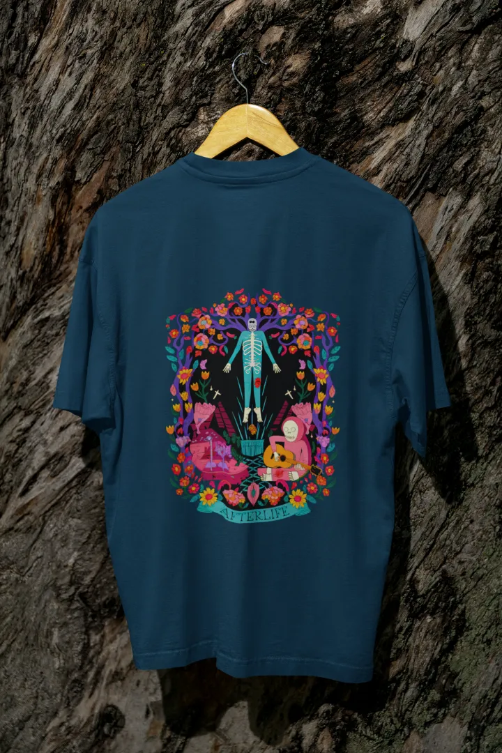 Navy Blue back printed oversized tee shirt for men hanging on a wooden hanger against a textured background, featuring a colorful psychedelic illustration of two figures—one standing and the other sitting on a bench surrounded by flowers and leaves in vibrant, intricate detail.