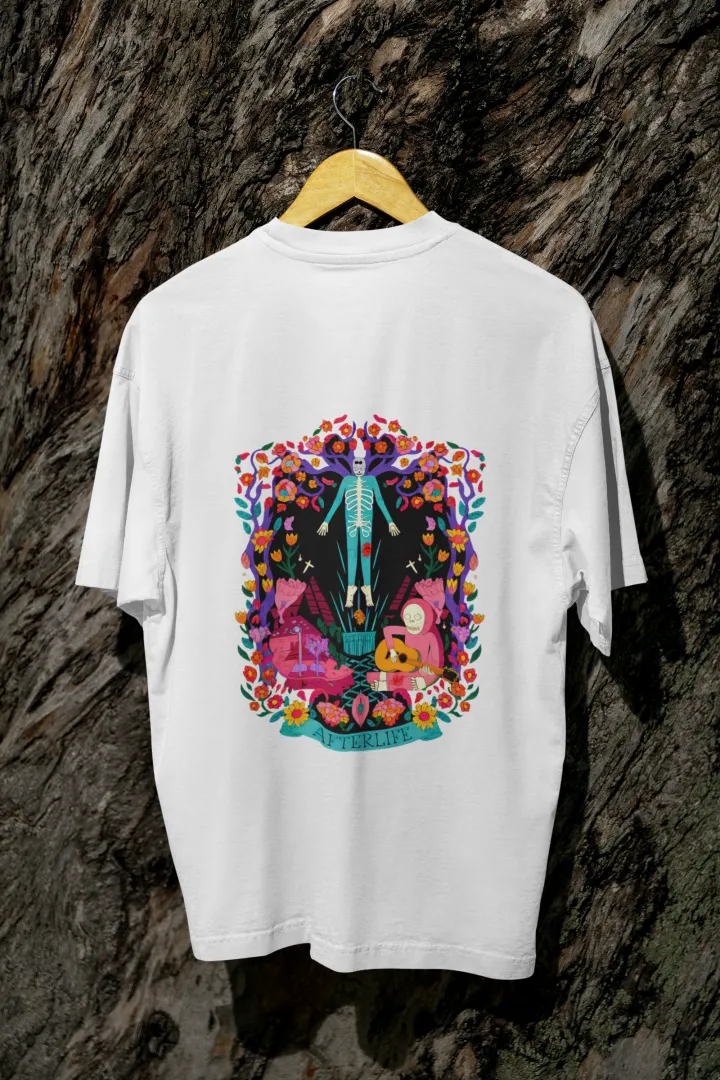 White back printed oversized tee shirt for men hanging on a wooden hanger against a textured background, featuring a colorful psychedelic illustration of two figures—one standing and the other sitting on a bench surrounded by flowers and leaves in vibrant, intricate detail.