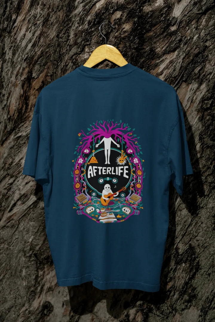 Navy Blue oversized tee shirt hanging on a wooden hanger against a textured background, featuring a colorful psychedelic circular design with the word 'Afterlife' at the top. The design includes a tree with pink and purple leaves, and a skull and crossbones, surrounded by vibrant, intricate details.