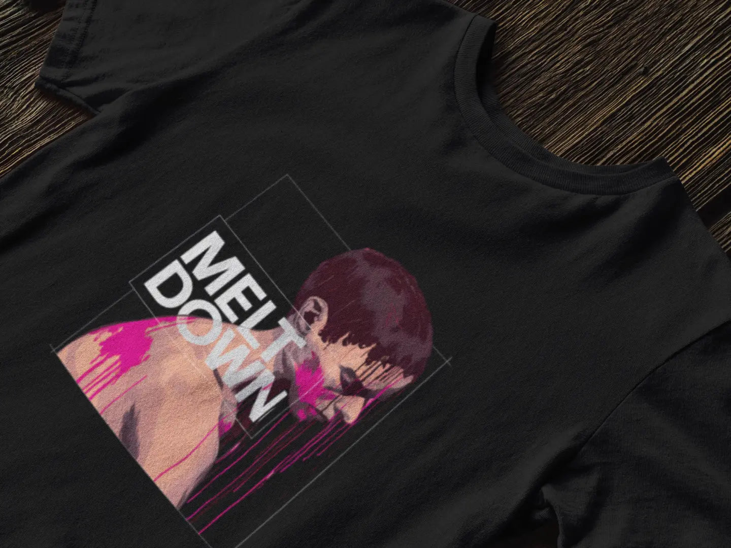 A black t-shirt with a graphic design of a somber man in a three-quarter view, with pink drips running down his body. White text reads “MELT DOWN”. The style is modern with a grunge aesthetic.