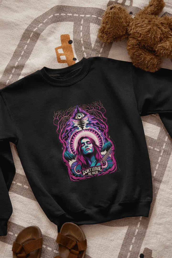 A black sweatshirt with a graphic design. Centered on the front is a stylized portrait of a woman with long purple hair, holding a guitar. She has a confident expression, and the design features vibrant purple, teal, and pink hues, with a surreal forest-like background of dark purple and teal trees. A stylized eye and the text “Don’t Leave Me High” are visible beneath her.