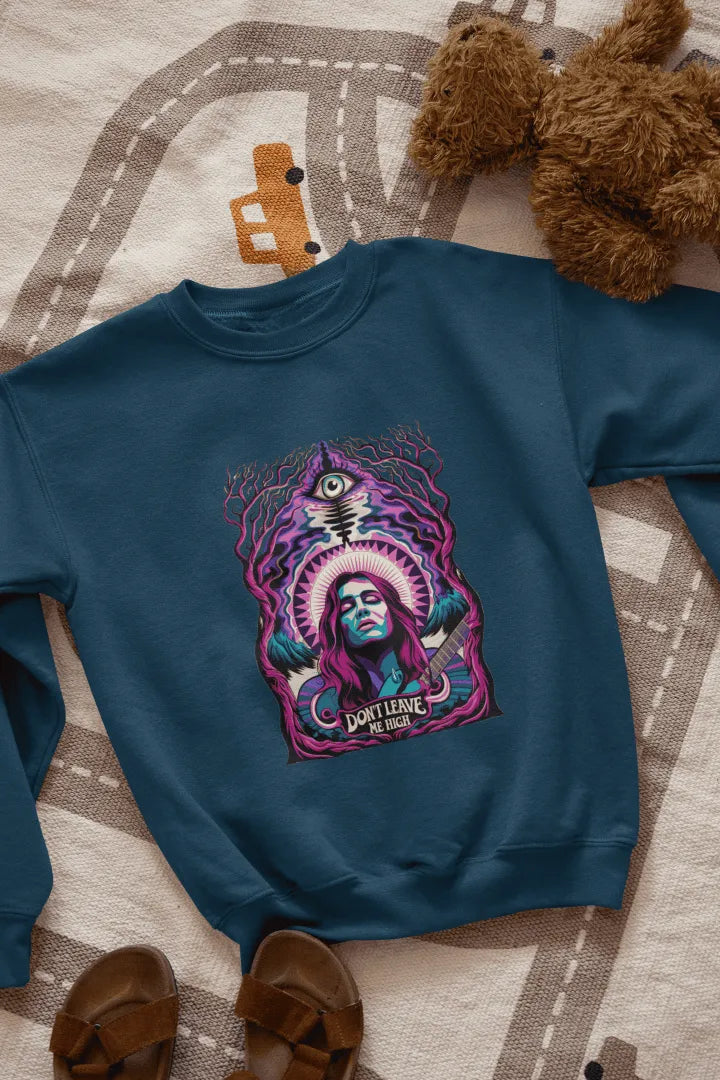 A navy blue sweatshirt with a graphic design. Centered on the front is a stylized portrait of a woman with long purple hair, holding a guitar. She has a confident expression, and the design features vibrant purple, teal, and pink hues, with a surreal forest-like background of dark purple and teal trees. A stylized eye and the text “Don’t Leave Me High” are visible beneath her.