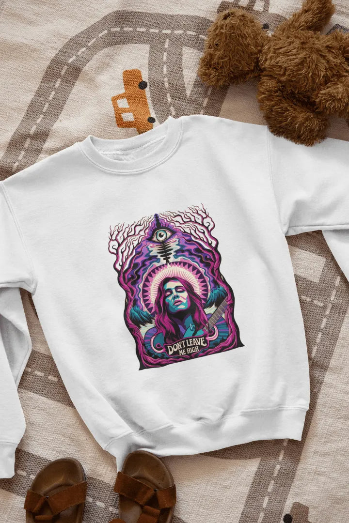 A white sweatshirt with a graphic design. Centered on the front is a stylized portrait of a woman with long purple hair, holding a guitar. She has a confident expression, and the design features vibrant purple, teal, and pink hues, with a surreal forest-like background of dark purple and teal trees. A stylized eye and the text “Don’t Leave Me High” are visible beneath her.