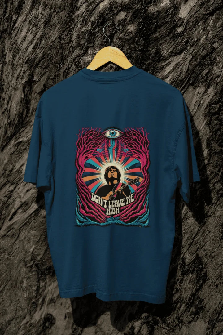 A navy blue t-shirt with a psychedelic graphic on the back, featuring a musician playing a guitar surrounded by vibrant swirling colors. The design includes a large stylized eye and the text “DON’T LEAVE ME HIGH,” evoking a 1960s/1970s psychedelic art style. The composition is centered, with harmonious lighting and a visually impactful atmosphere.
