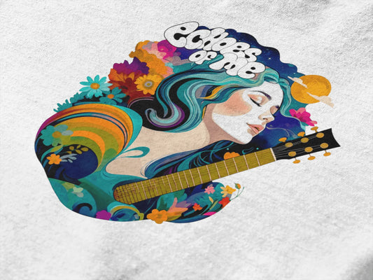 A white oversized T-shirt featuring a vibrant graphic design of a young woman with teal-colored hair, centered on the back. The artwork depicts her in a dreamy pose, leaning over a guitar intricately patterned with floral and abstract designs. The background blends celestial and floral elements with shades of teal, purple, pink, orange, and yellow, creating a vivid, psychedelic atmosphere. The text “Echoes of Me” is written.