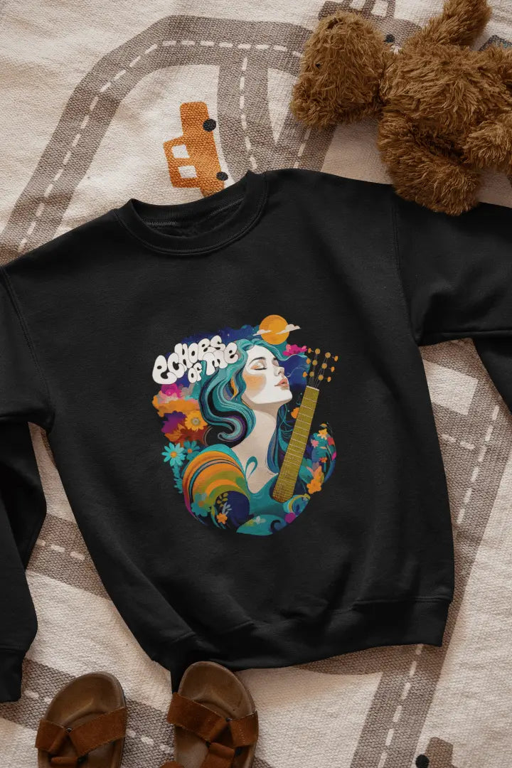 A black sweatshirt with a vibrant graphic of a woman with flowing teal hair holding a guitar, surrounded by floral and swirling patterns in teal, orange, and cream tones. The text “Echoes of Me” appears above the design, evoking a 1960s-70s aesthetic. Soft and calming atmosphere.