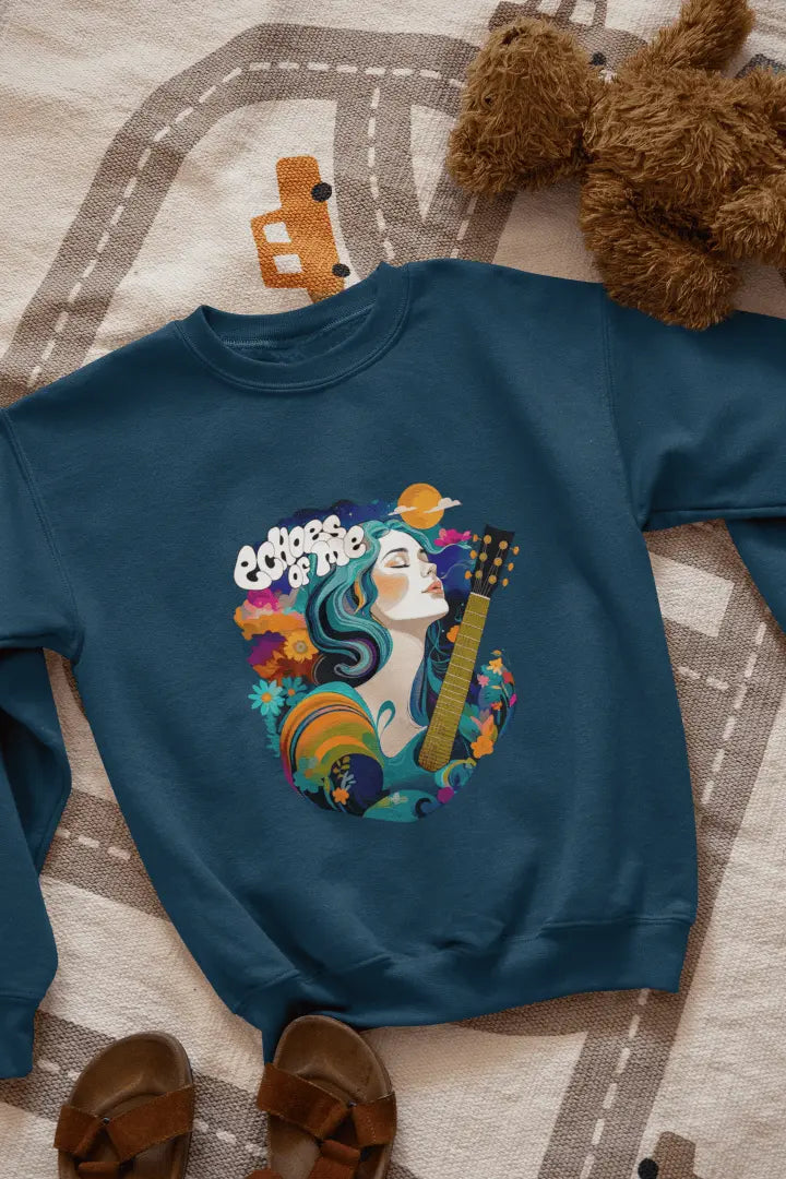 A navy blue sweatshirt with a vibrant graphic of a woman with flowing teal hair holding a guitar, surrounded by floral and swirling patterns in teal, orange, and cream tones. The text “Echoes of Me” appears above the design, evoking a 1960s-70s aesthetic. Soft and calming atmosphere.