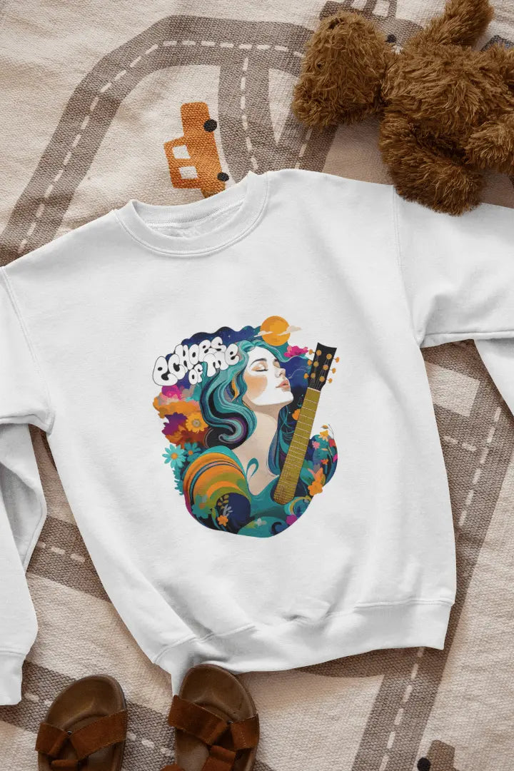 A white sweatshirt with a vibrant graphic of a woman with flowing teal hair holding a guitar, surrounded by floral and swirling patterns in teal, orange, and cream tones. The text “Echoes of Me” appears above the design, evoking a 1960s-70s aesthetic. Soft and calming atmosphere.
