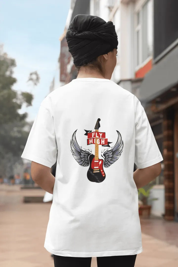 A girl wearing a white oversized t-shirt with a design printed on the back. The design contains a guitar with wings. There's a text saying Fly High at the center top of the design.