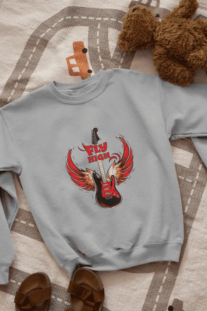 A grey sweatshirt with a graphic design of a red electric guitar with fiery red wings, and the words “Fly High” in bold, red letters above it. The sweatshirt is laid flat on a beige-gray patterned rug with road markings, with brown sandals on either side. The lighting is soft and natural, giving the overall look a casual, fun style.