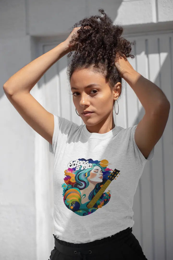 A girl with curly hair wearing a white T-shirt. The T-shirt consists of a psychedelic design of a girl holding a guitar. There’s a text saying echoes of me.