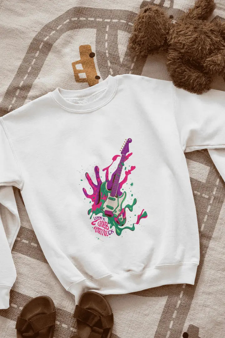 A white sweatshirt kept on the floor containing a psychedelic design pattern. The design contains of guitar made up of paint splashes, and a hand at the back, trying to grab it There is a text saying let me grab that neck.
