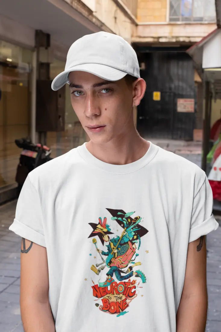 A man wearing a white cap and a printed white T-shirt. The design contains a character with a microphone in his hands. There’s a text saying Neurotic to The Bone at the bottom of the design.