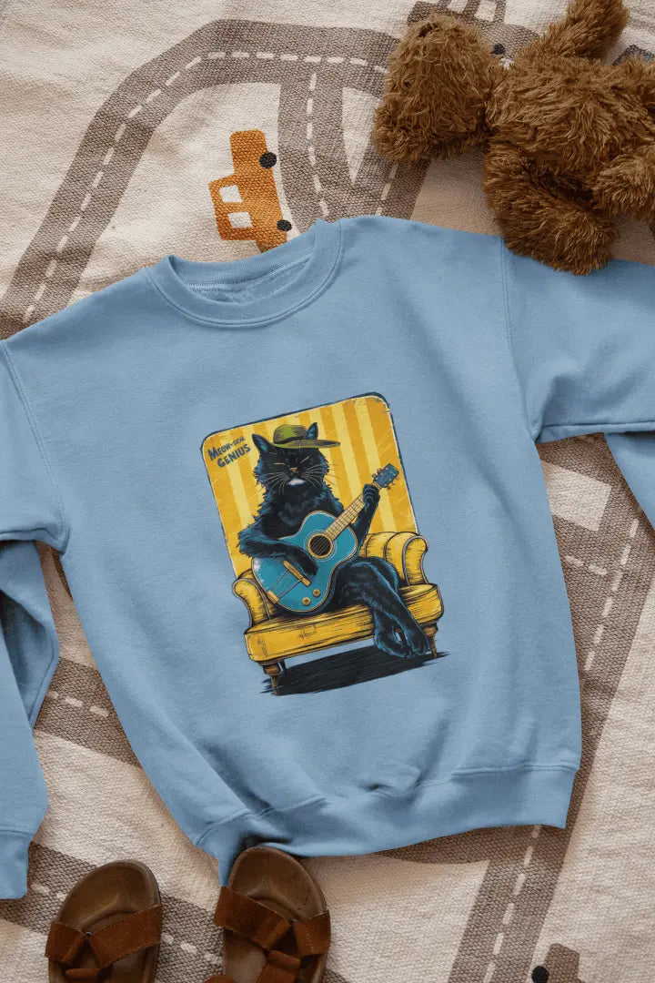 A baby blue printed sweatshirt with the design of a cat wearing a cute cap and playing a guitar while sitting on a sofa. The sweatshirt is lying down on the floor. There’s a text saying meowsical genius.