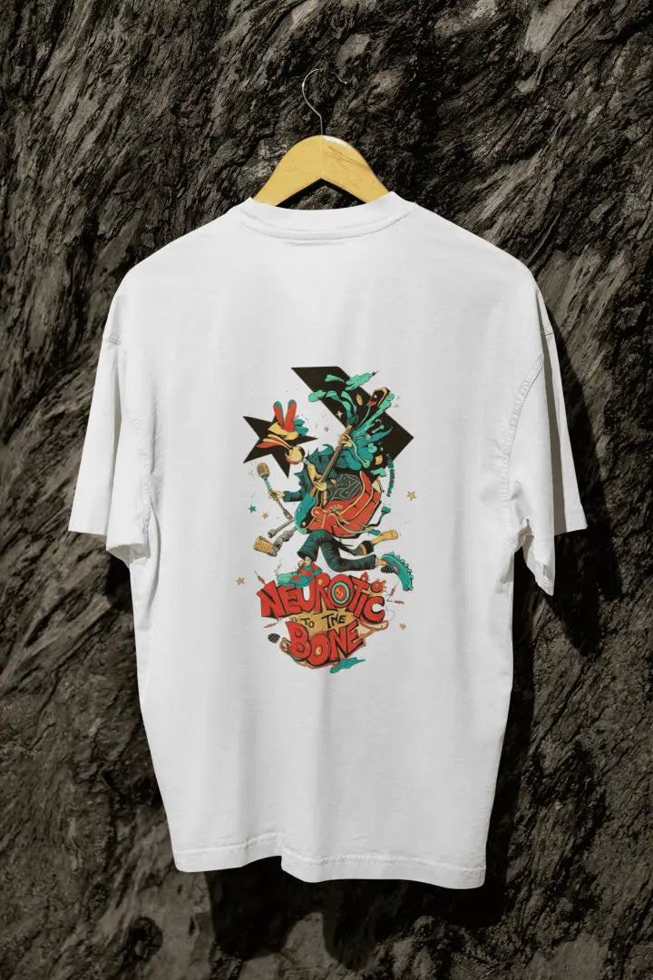 A white back printed oversized T-shirt with a hanging against a tree trunk. The T-shirt design contains of a funky character with an instrument and a microphone in his hand. There’s a text saying “Neurotic to the bone”.