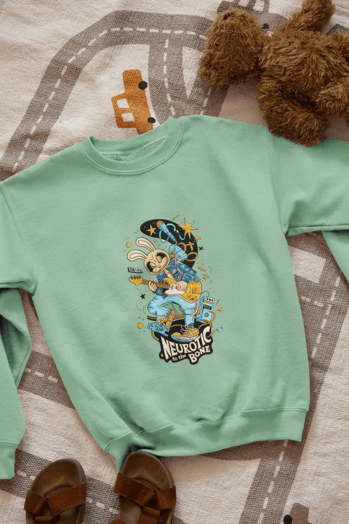 A green sweatshirt with a printed design lying on the floor. The design contains of a funky character playing a guitar. There’s a text saying “Neurotic to the bone” at the bottom of the design.