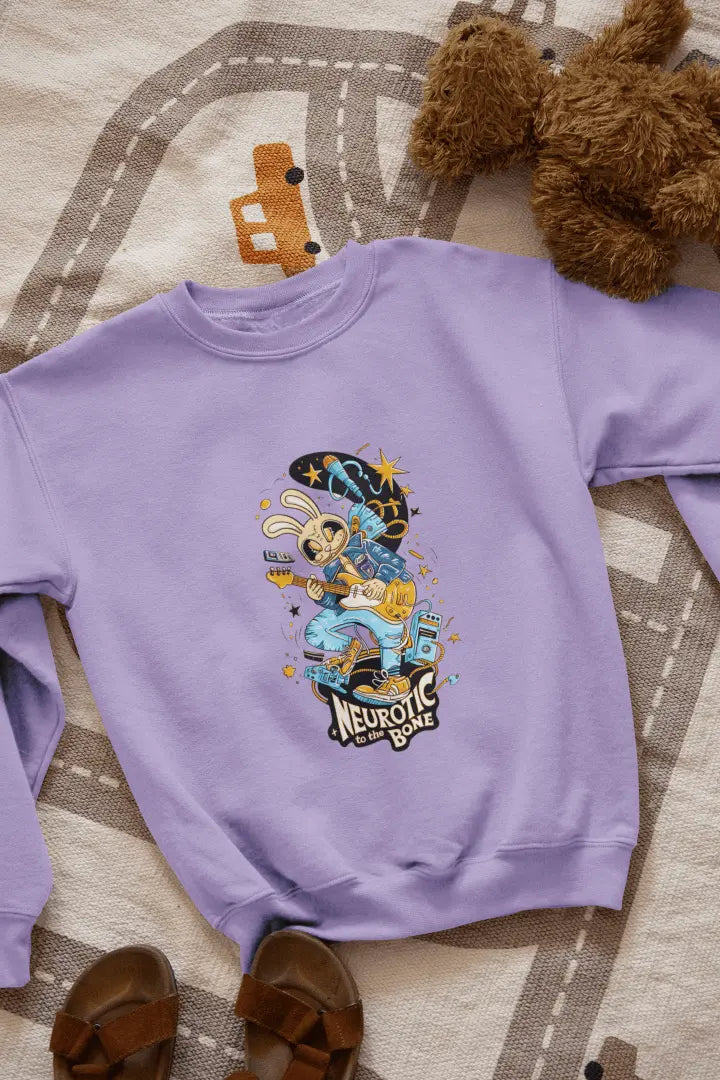 A lavender sweatshirt with a printed design lying on the floor. The design contains of a funky character playing a guitar. There’s a text saying “Neurotic to the bone” at the bottom of the design.