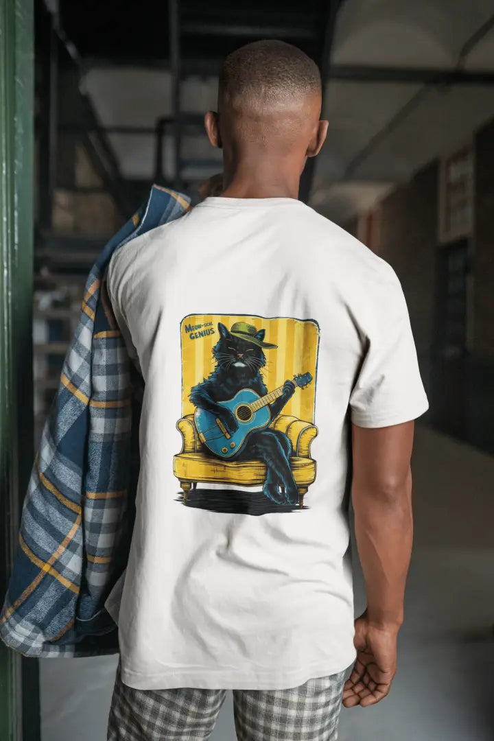 A man wearing a white back printed oversized t-shirt. The print design contains a cat wearing a hat and sitting on the sofa. There's a text saying Meowsical Genius on the top left of the design.