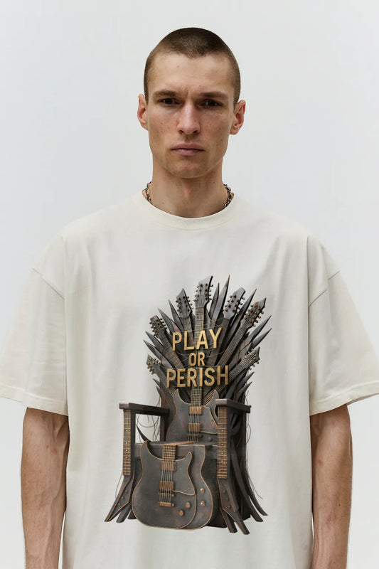 Man wearing a white t-shirt with 'Play or Perish' graphic design on a plain background