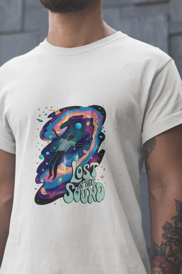 Close up of a man wearing a white t-shirt with a design printed on the front. The design contains a man floating in space with planets and stars around him. There's a text saying Lost In The Sound at the bottom right of the design.