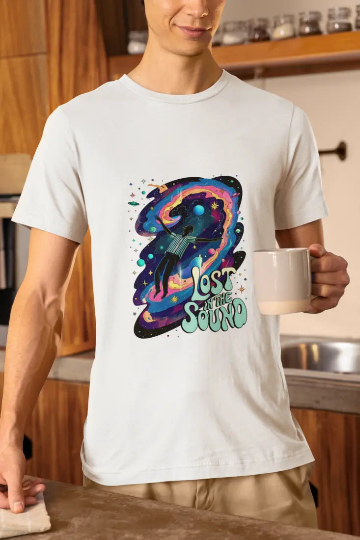 A man wearing a white t-shirt with a design printed on the front. The design contains a man floating in space with planets and stars around him. There's a text saying Lost In The Sound at the bottom right of the design.
