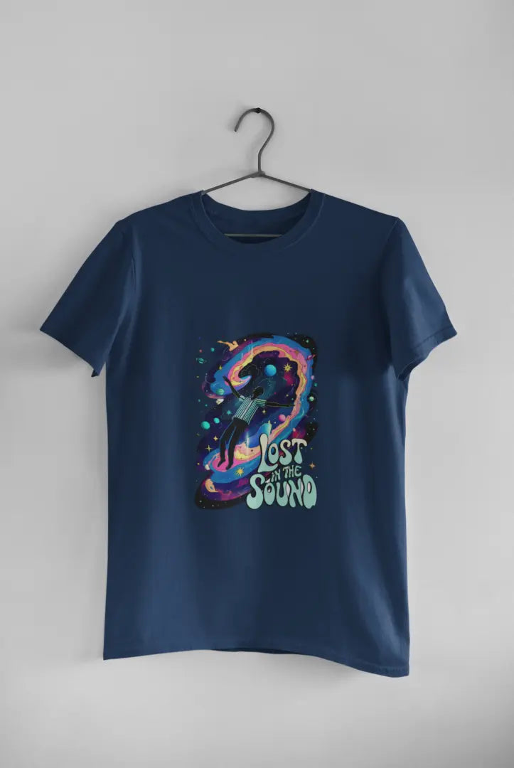 A navy blue t-shirt with a design printed on the front hanging against a light grey wall. The design contains a man floating in space with planets and stars around him. There's a text saying Lost In The Sound at the bottom right of the design.