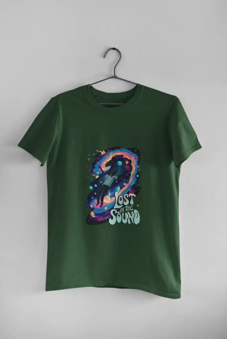 An olive green t-shirt with a design printed on the front hanging against a light grey wall. The design contains a man floating in space with planets and stars around him. There's a text saying Lost In The Sound at the bottom right of the design.