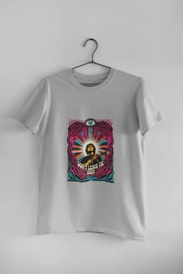 A grey t-shirt with a psychedelic design printed on the front hanging against a light grey wall. The design contains a man playing guitar with his eyes closed. The overall design is psychedelic with an eye at the top and a text saying Don't leave me high at the bottom of the design.
