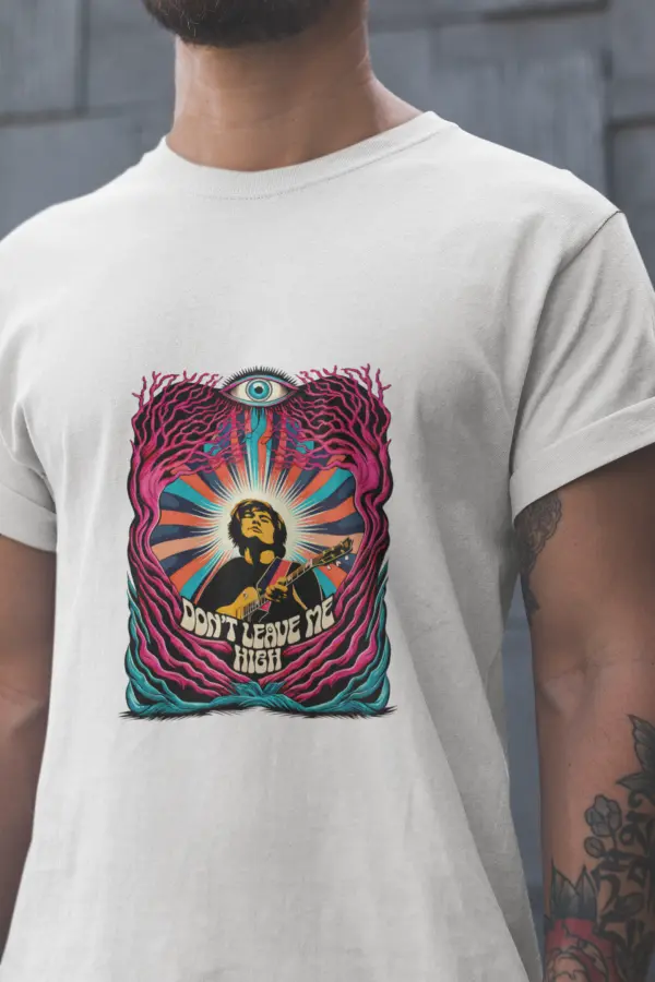 Close up shot of a man wearing a white t-shirt with a psychedelic design printed on the front. The design contains a man playing guitar with his eyes closed. The overall design is psychedelic with an eye at the top and a text saying Don't leave me high at the bottom of the design.