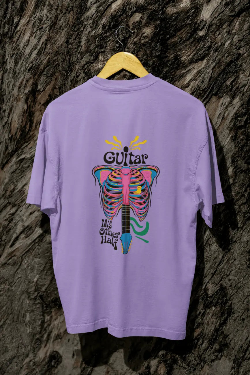 A lavender back printed oversized t-shirt with a psychedelic guitar design  hanging on a tree trunk