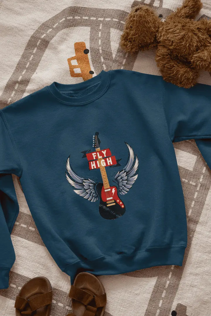 A navy blue sweatshirt with a graphic design of a black electric guitar with gray and white angel wings, and a red “FLY HIGH” banner. The sweatshirt is laid flat on a light beige road-patterned rug, with brown leather sandals at the bottom left. Soft lighting highlights the graphic, creating a relaxed, casual atmosphere.