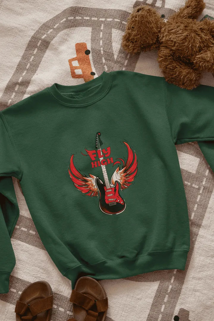 A green sweatshirt with a graphic design of a red electric guitar with fiery red wings, and the words “Fly High” in bold, red letters above it. The sweatshirt is laid flat on a beige-gray patterned rug with road markings, with brown sandals on either side. The lighting is soft and natural, giving the overall look a casual, fun style.