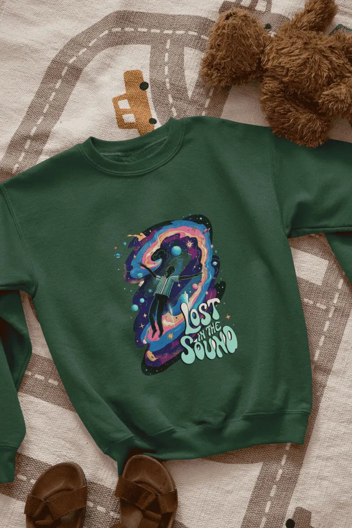 A green sweatshirt lying on the floor. The sweatshirt contains a design of a man floating in space. There is a text saying lost in the sound.