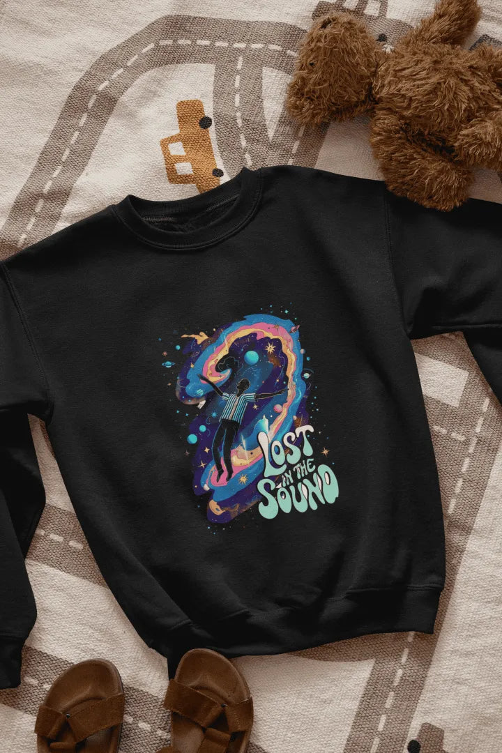 A black sweatshirt lying on the floor. The sweatshirt contains a design of a man floating in space. There is a text saying lost in the sound.