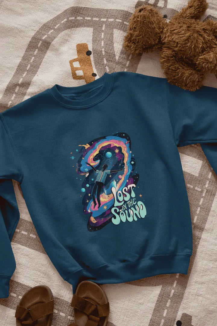 A navy blue sweatshirt lying on the floor. The sweatshirt contains a design of a man floating in space. There is a text saying lost in the sound.