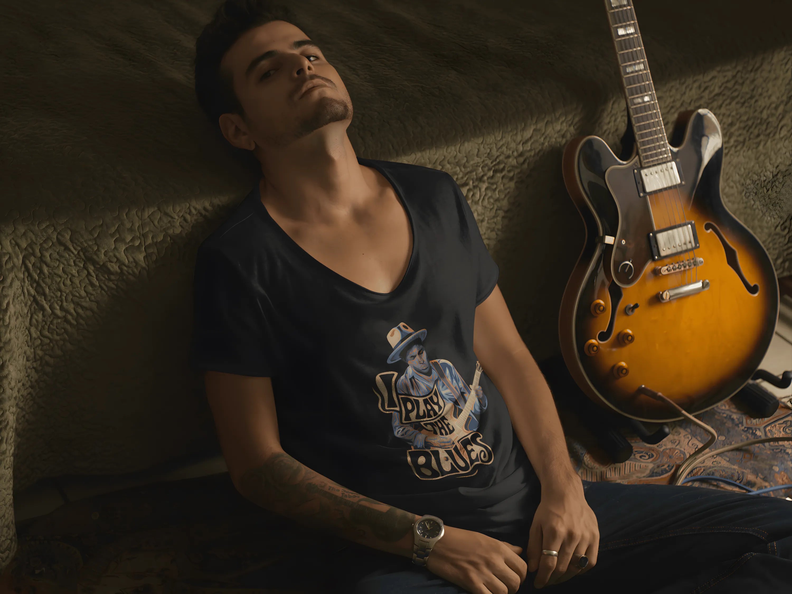 Man sitting next to a guitar with a dark background