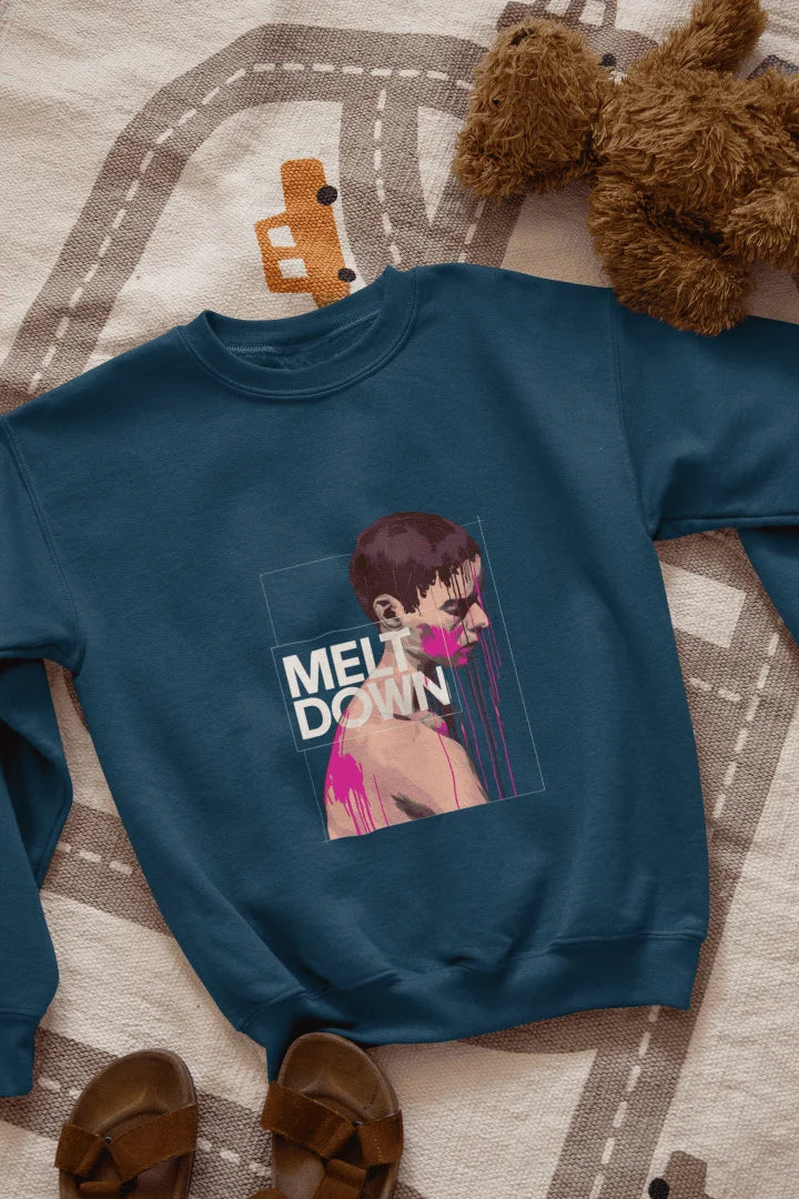 A navy blue sweatshirt lying on the floor containing the design of a man in grief. The man is covered in pink paint splashes with paint dripping down from his face. There’s a text saying Meltdown on the design. 