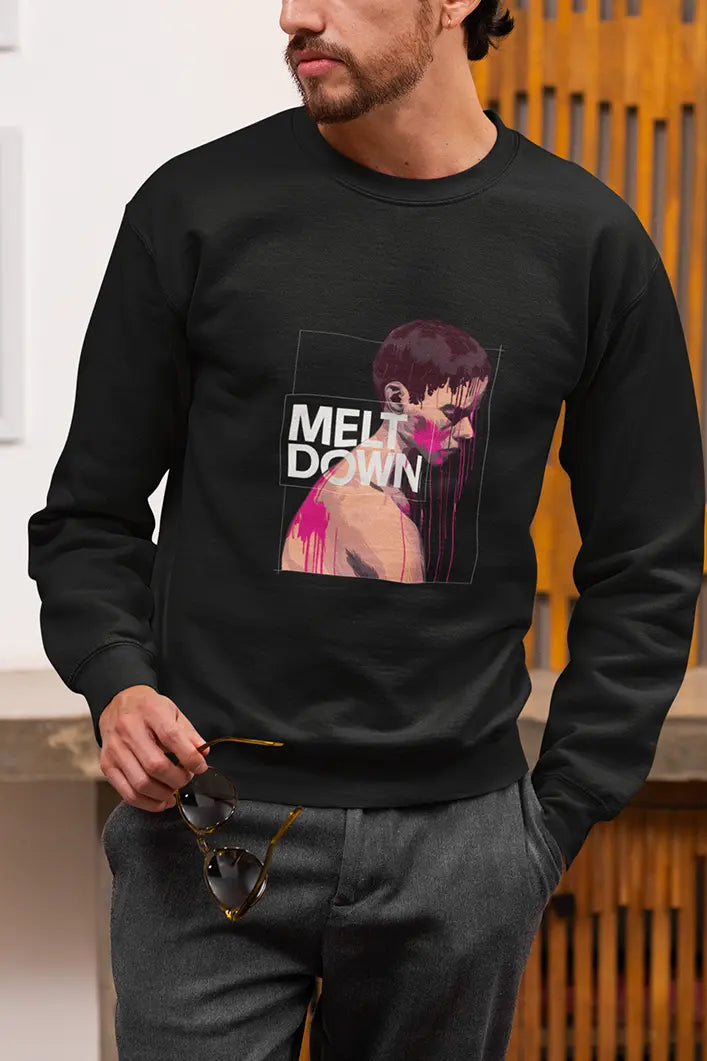A man wearing a black sweatshirt with an abstract design of a man in grief covered in pink paint splashes. There’s a text saying Meltdown.