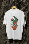 A white back printed oversized T-shirt with a hanging against a tree trunk. The T-shirt design contains of a funky character with an instrument and a microphone in his hand. There’s a text saying “Neurotic to the bone”.