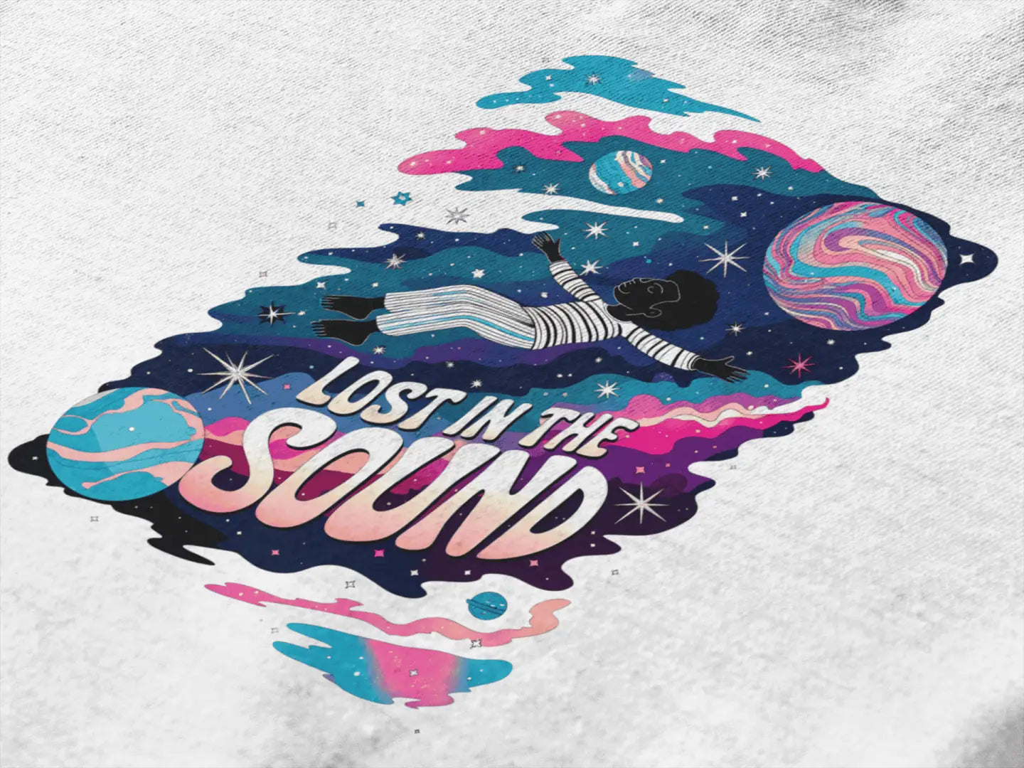 Close up of a design printed on a t-shirt. The print design contains a kid floating in space with planets and starts surrounding him. There is a text saying Lost In The Sound on the design.