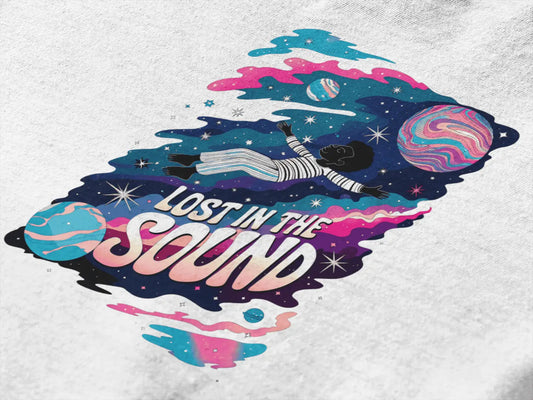 Close up of a design printed on a t-shirt. The print design contains a kid floating in space with planets and starts surrounding him. There is a text saying Lost In The Sound on the design.