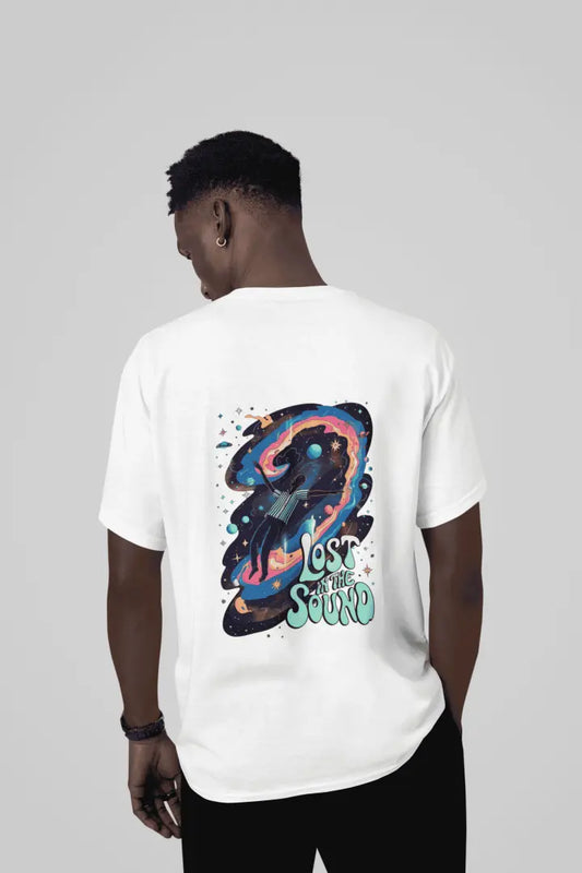 A man wearing a white back printed oversized t-shirt with a back print. The back print contains a man floating in space with planets and stars around him. There's a text saying Lost in The Sound on the bottom right of the design.