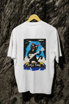 A white back printed oversized t-shirt with a back print hanging from a tree trunk. The design contains a cat holding a fish bone like a guitar and appears to play it aggressively. There's a text saying Solo Time at the bottom of the design.