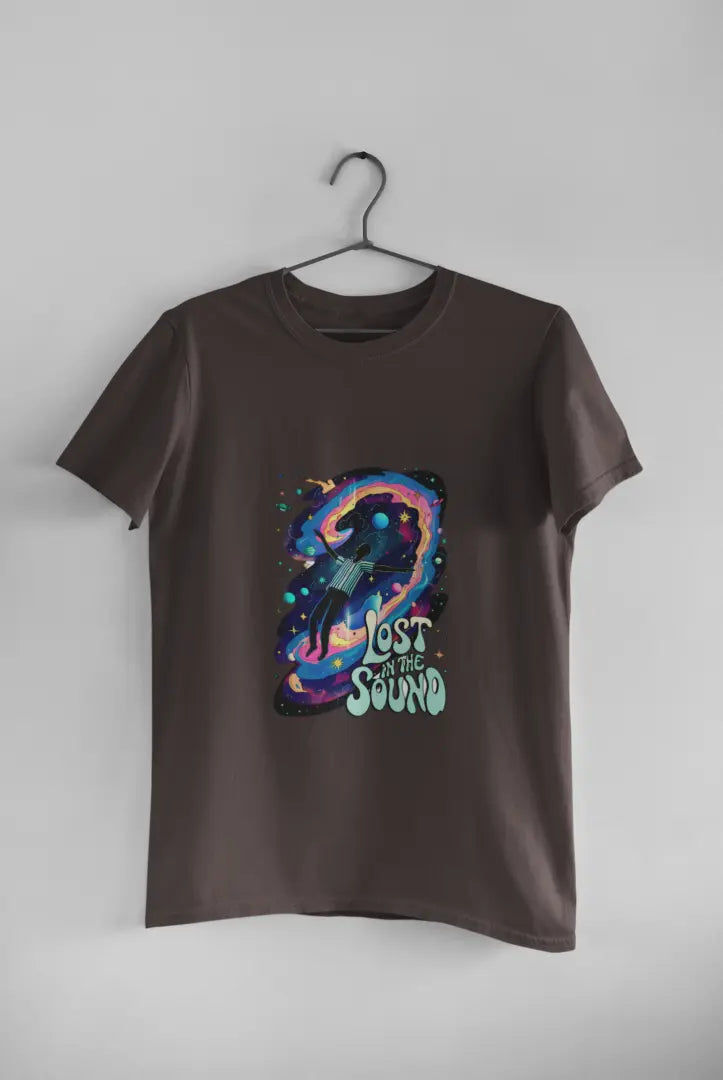 A black t-shirt with a design printed on the front hanging against a light grey wall. The design contains a man floating in space with planets and stars around him. There's a text saying Lost In The Sound at the bottom right of the design.