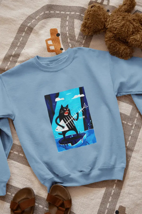 A baby blue sweatshirt with a design printed on the front lying on the floor. The design contains a cat standing on an iceberg holding a fish bone which appears to be like a guitar. There's a text saying Solo Time on the right side.