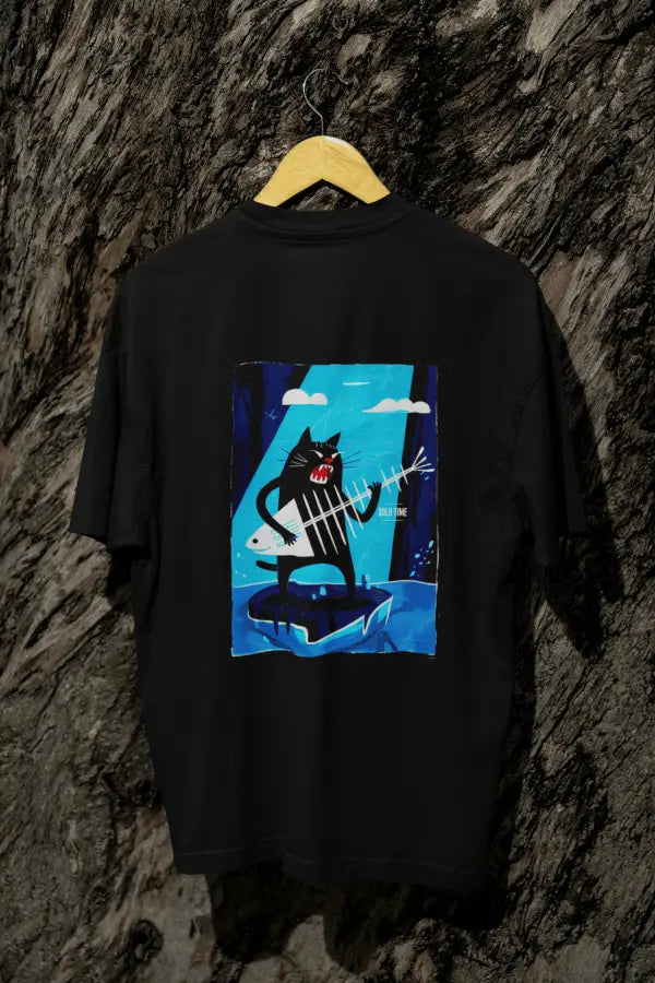 A black oversized t-shirt with a design printed on the back hanging against a tree trunk. The design contains a cat holding a fish bone like a guitar and appearing to play it aggressively. There's a text saying Solo Time on the right side of the design.