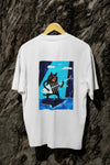 A white oversized t-shirt with a design printed on the back hanging against a tree trunk. The design contains a cat holding a fish bone like a guitar and appearing to play it aggressively. There's a text saying Solo Time on the right side of the design.
