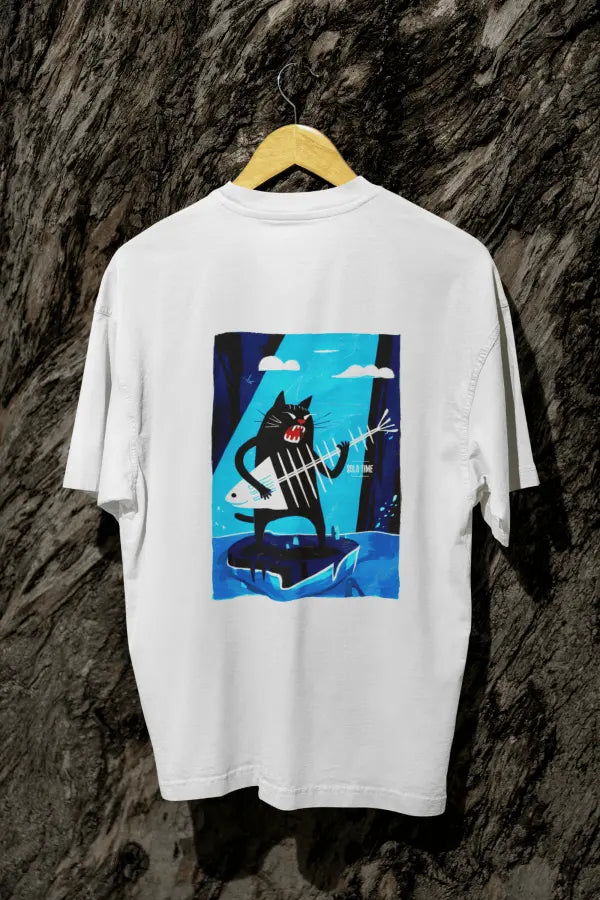 A white oversized t-shirt with a design printed on the back hanging against a tree trunk. The design contains a cat holding a fish bone like a guitar and appearing to play it aggressively. There's a text saying Solo Time on the right side of the design.